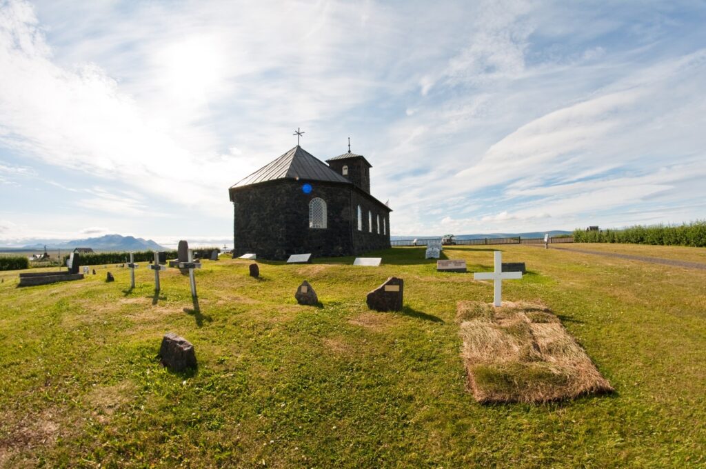 fresh grave by stone church in the country